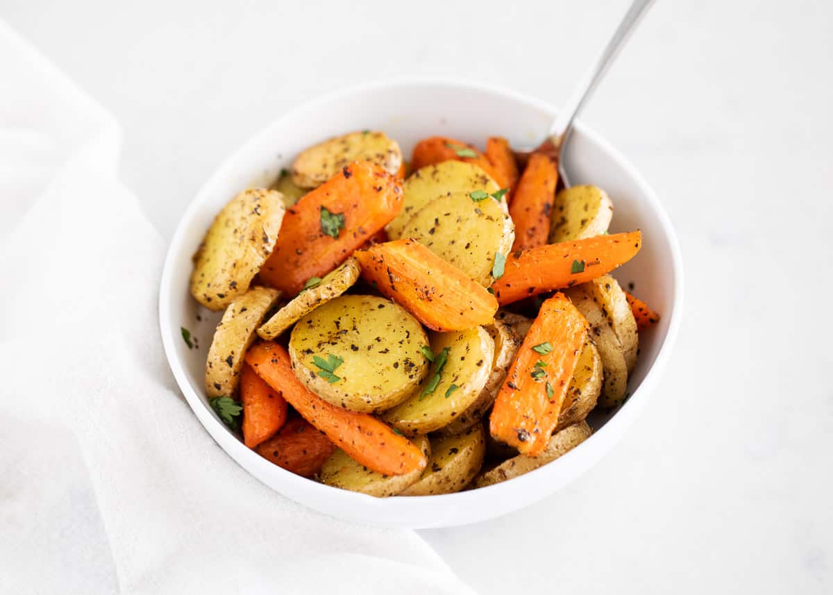 These oven roasted potatoes and carrots are crispy, tender and loaded with flavor in every bite. An easy side dish made in just one pan with only 5 minutes of prep! Roasted potatoes and carrots in bowl.