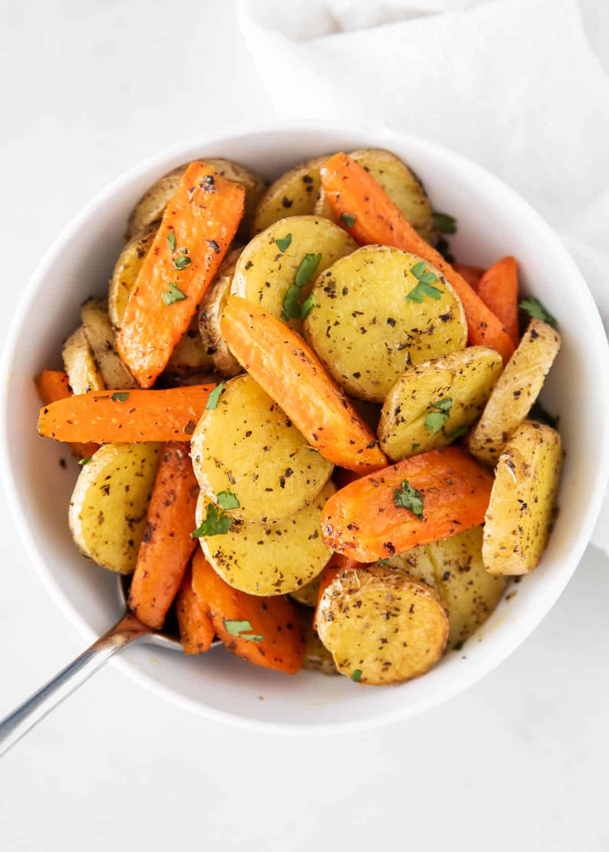 These oven roasted potatoes and carrots are crispy, tender and loaded with flavor in every bite. An easy side dish made in just one pan with only 5 minutes of prep! Roasted potatoes and carrots in bowl.