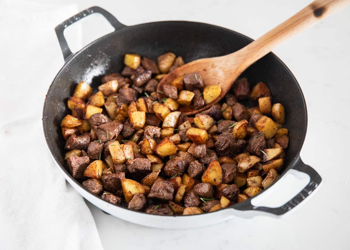 Steak and potatoes in pan.