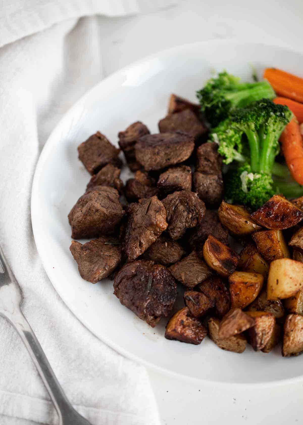 Steak bites on white plate.