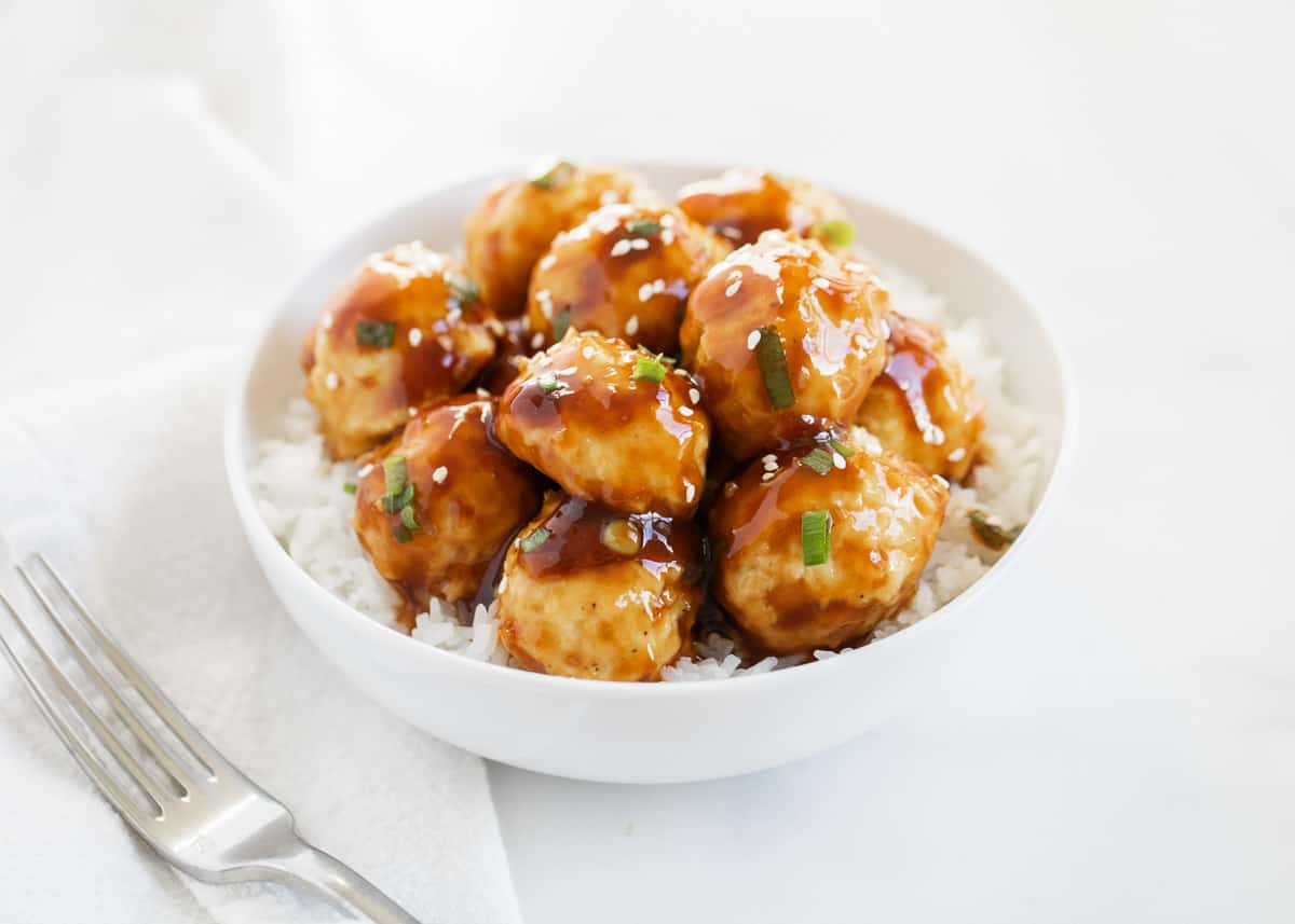 Teriyaki meatballs in a white bowl with rice.