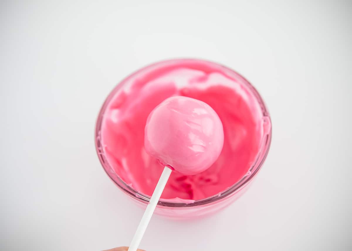 Dipping cake pop in pink melted chocolate.