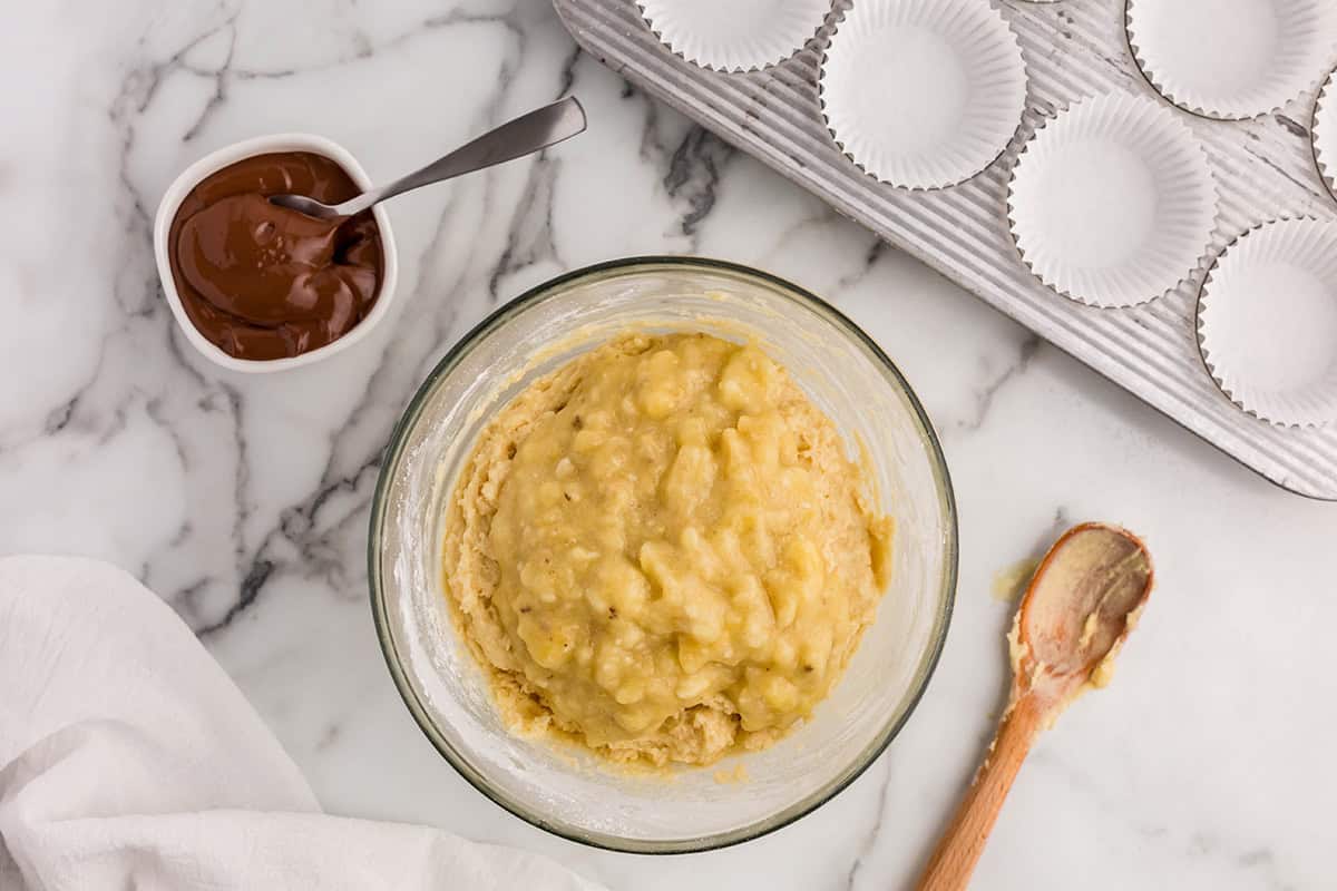 Banana muffin batter on the counter with Nutella in a small bowl.