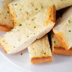Sliced garlic bread on white plate.