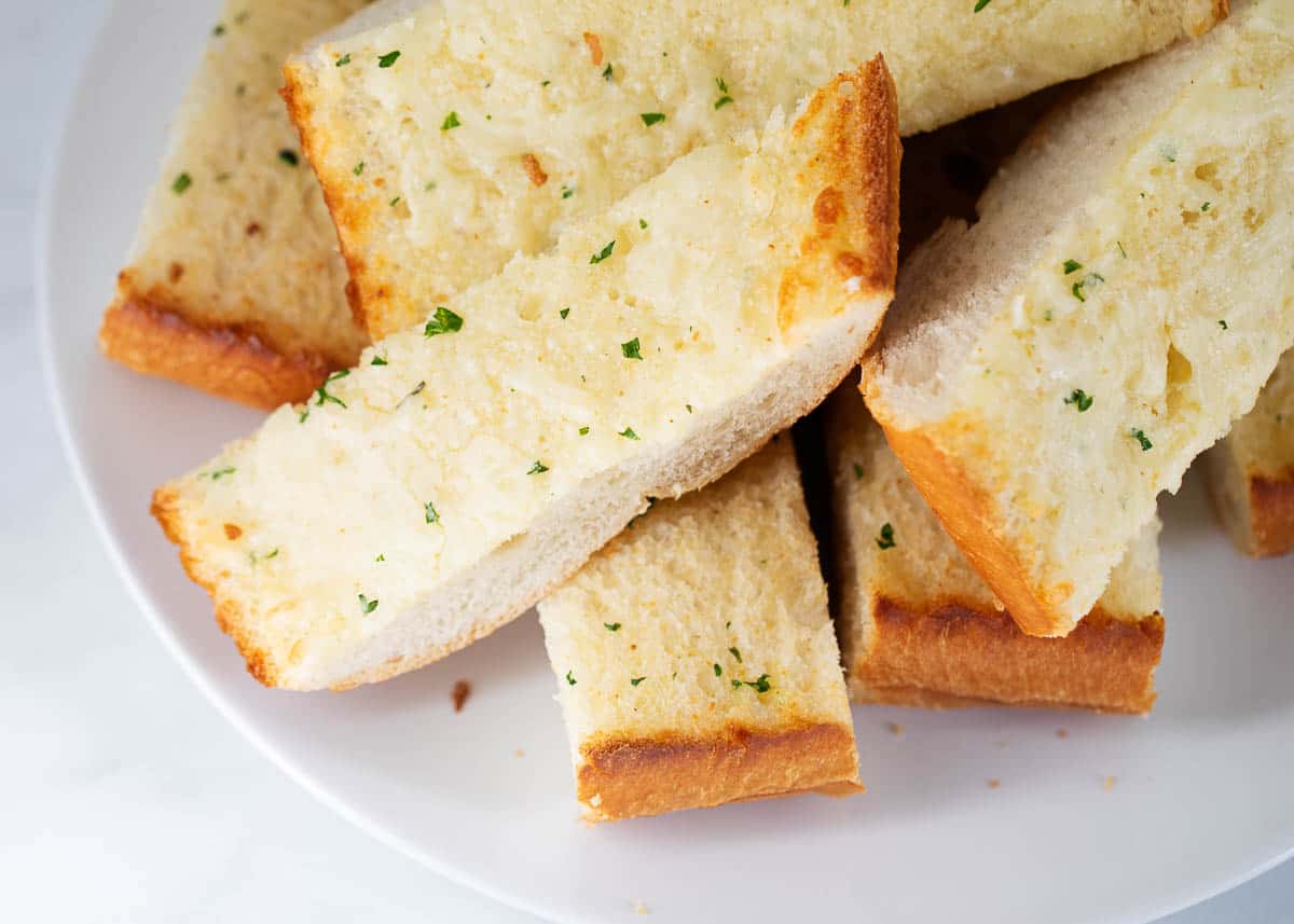 Sliced garlic bread on white plate. 