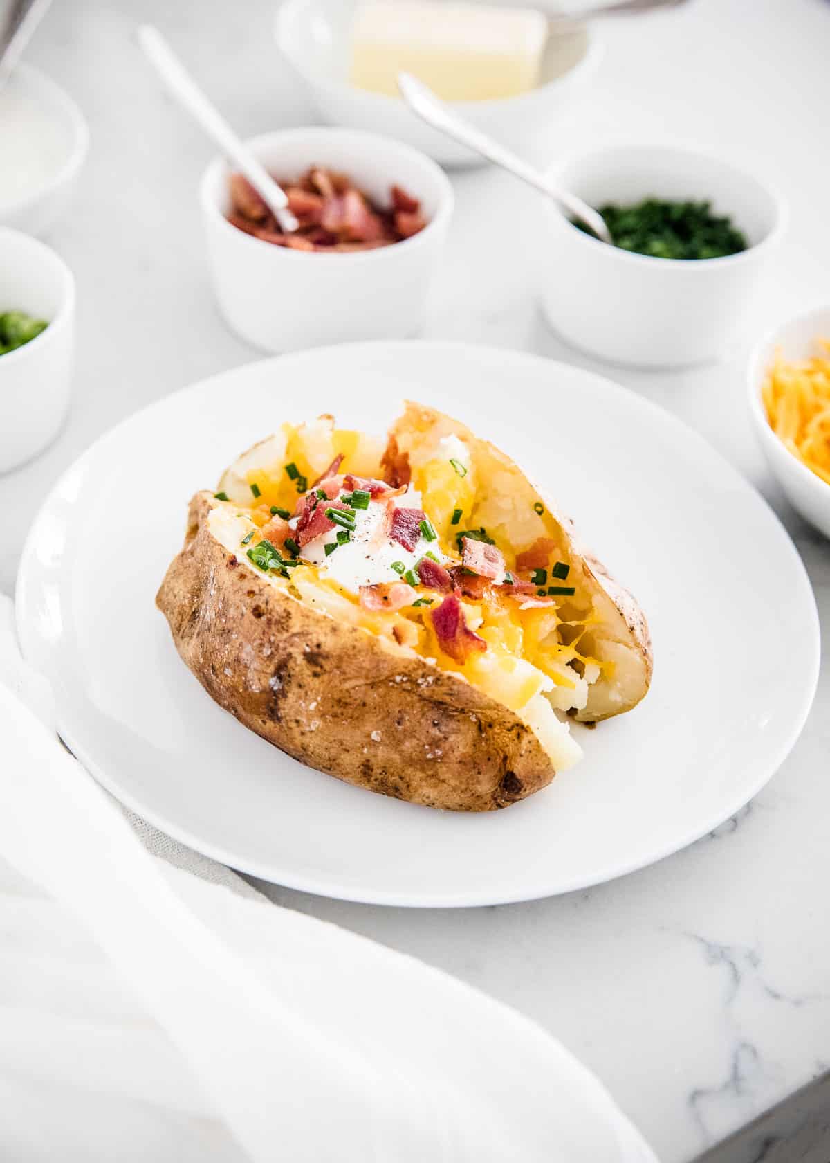 Loaded baked potato on white plate.