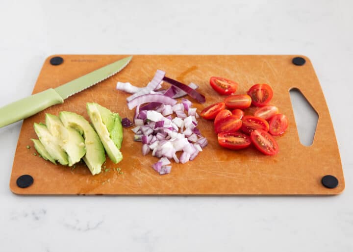 chopped avocado, red onion and tomato on cutting board 