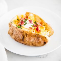 Loaded baked potato on white plate.