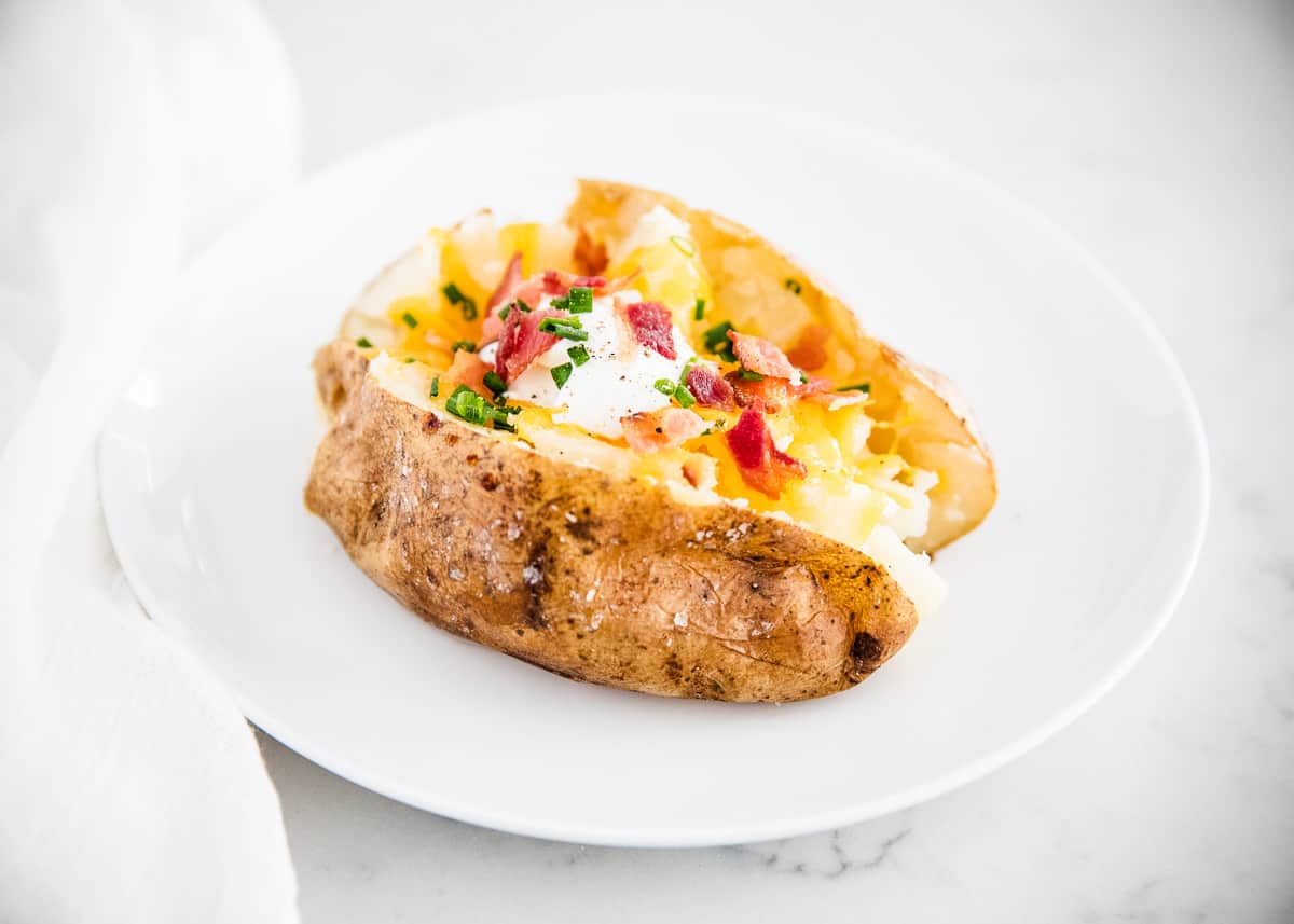 Loaded baked potato on white plate.