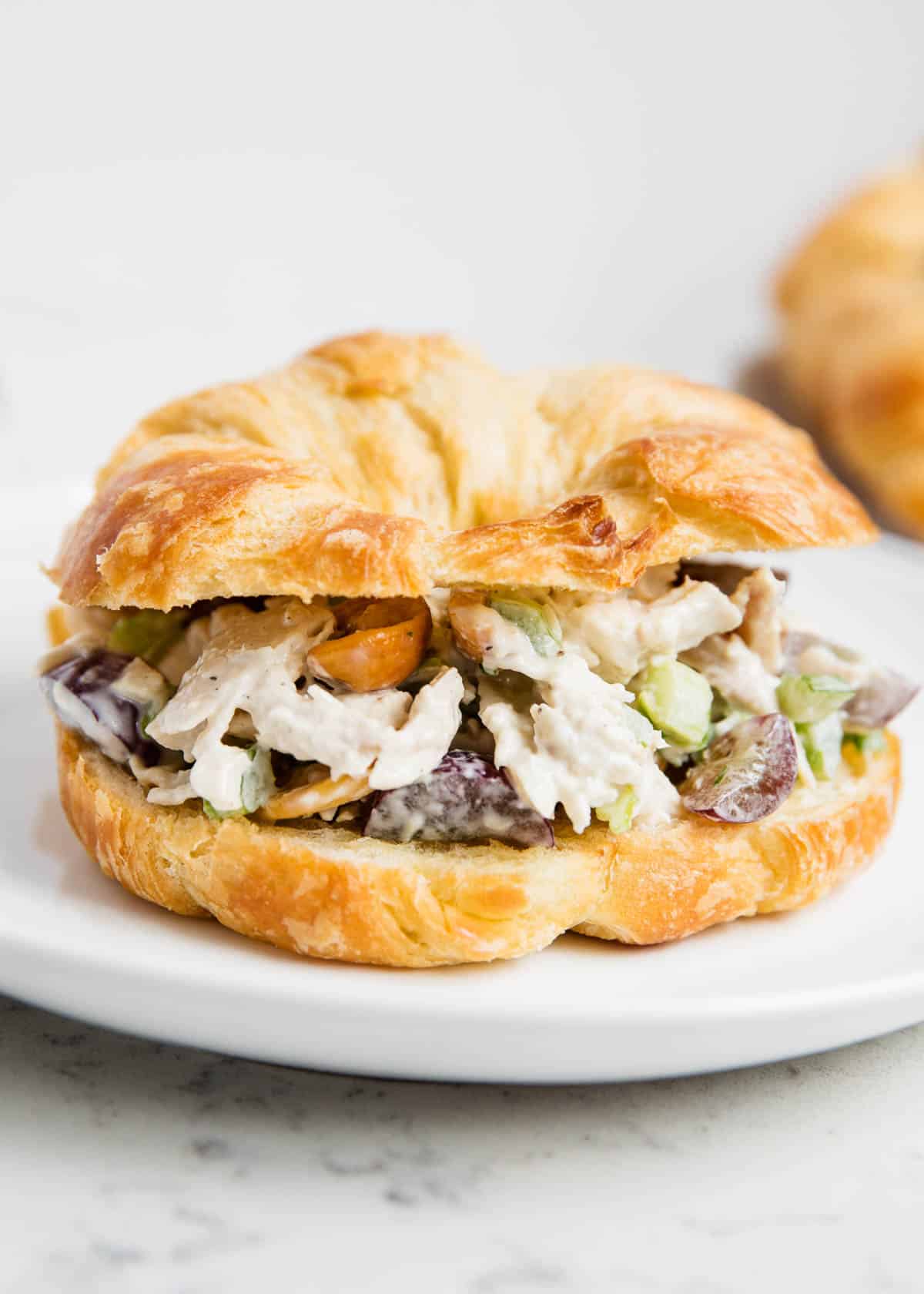 Chicken salad croissant on white plate.