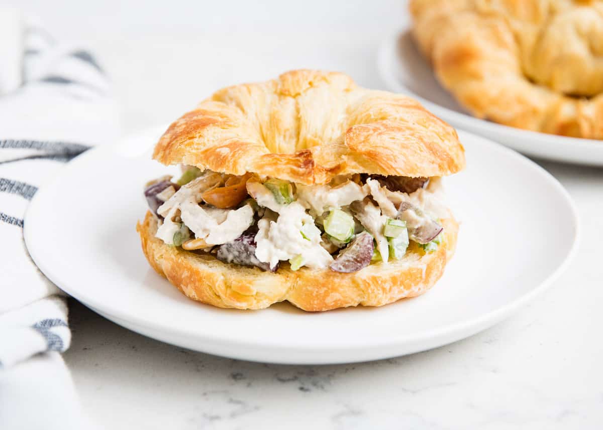 Chicken salad croissant on white plate.