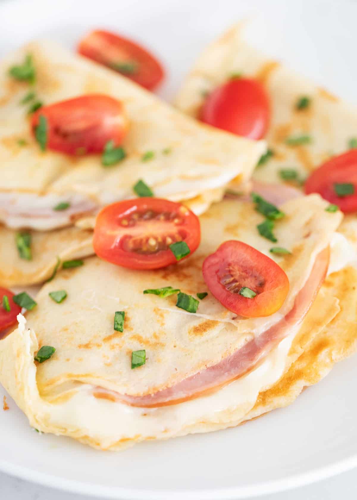 Ham and cheese crepe on white plate.