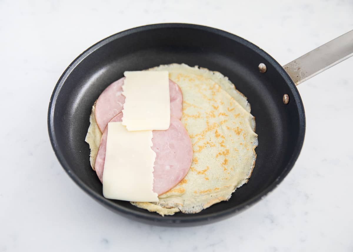 Ham and cheese crepe ingredients on pan.