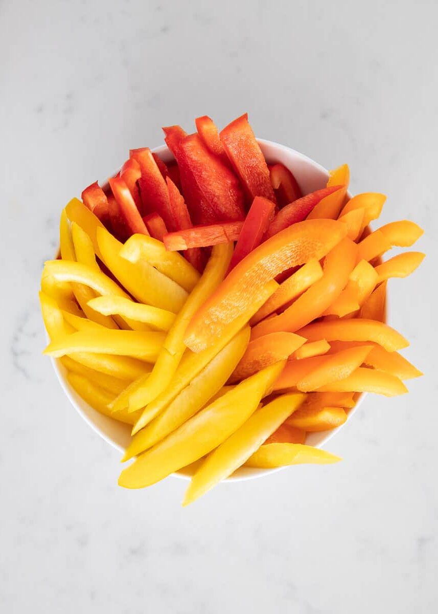 Sliced bell peppers in white bowl.