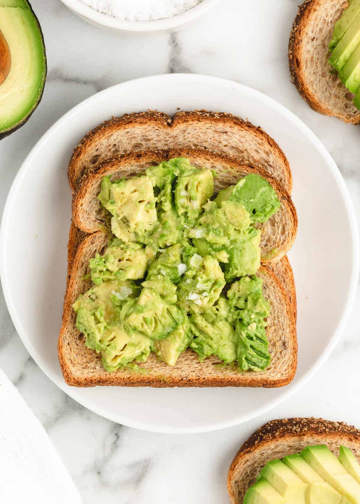 Avocado toast on white plate.