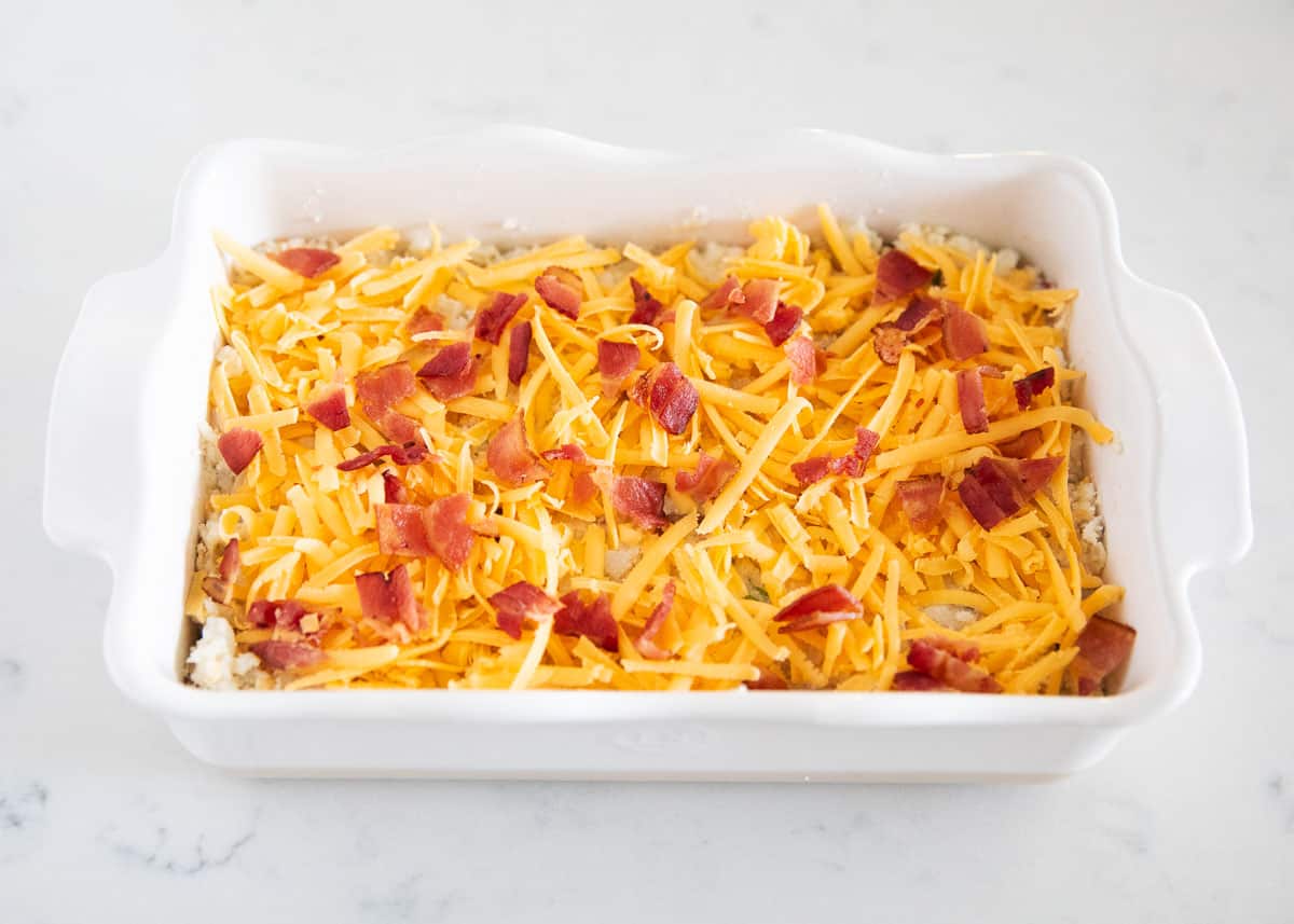 Assembled loaded baked potato casserole in white baking dish.