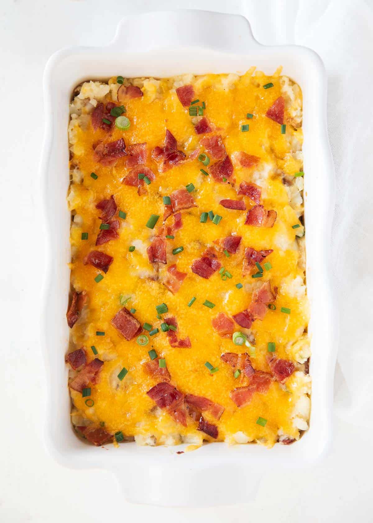 The best loaded baked potato casserole in baking dish on a white platter.