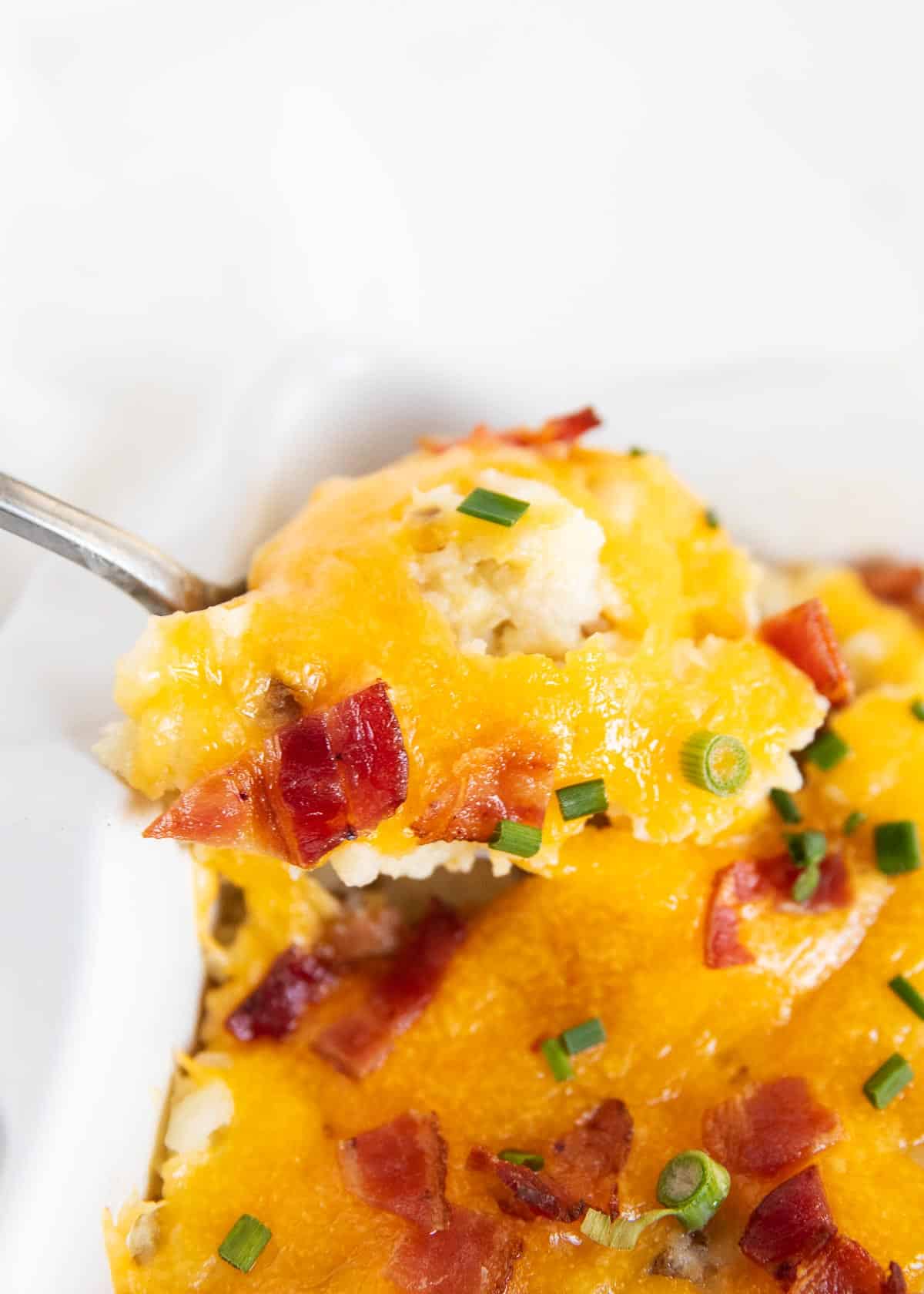 Loaded baked potato casserole close up on a spoon.