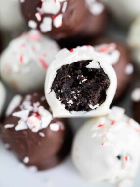 Close up of peppermint Oreo balls with a bit removed to show oreo truffle with chocolate coating and crushed candy canes.