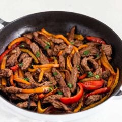 Steak fajita marinade strips cooked with bell peppers in a cast iron skillet.