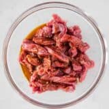 steak being marinated in bowl