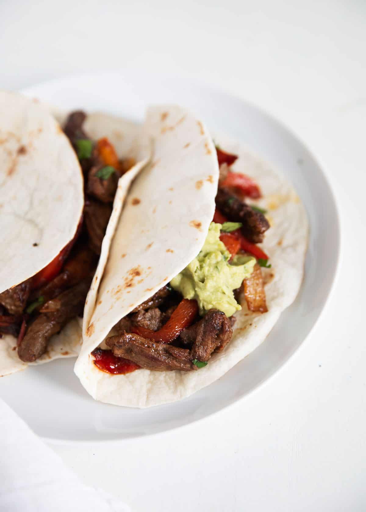 Steak fajitas on white plate.