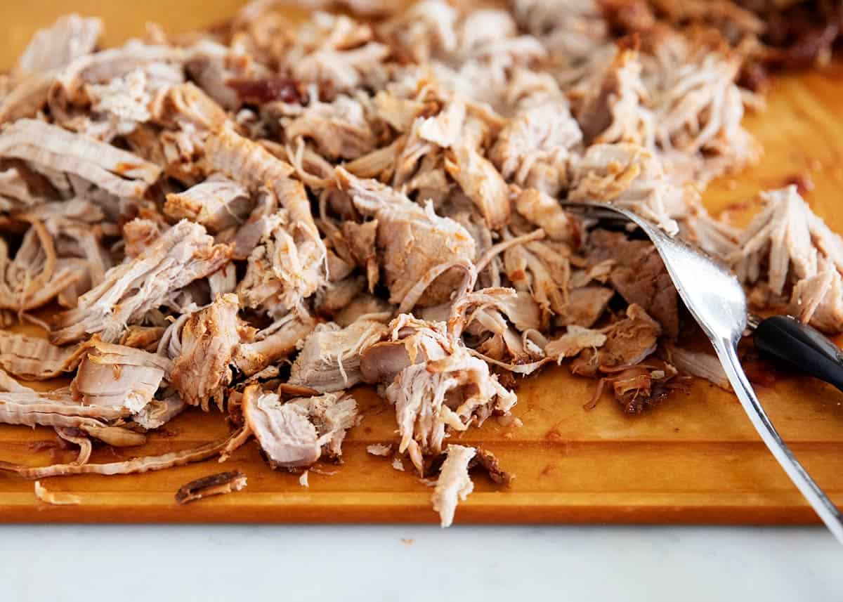 Pulled pork on wooden cutting board.