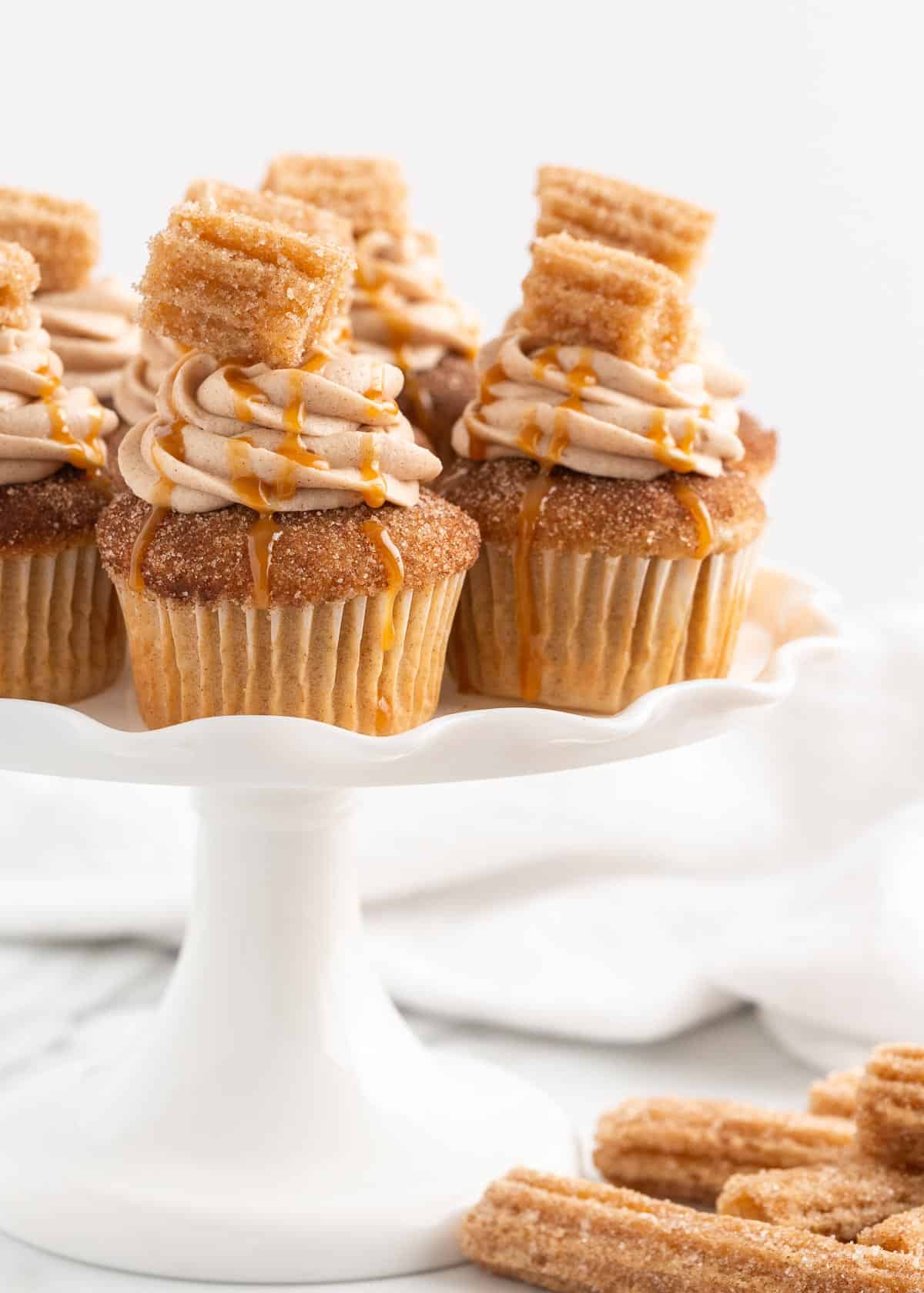 Churro cupcakes on white platter.