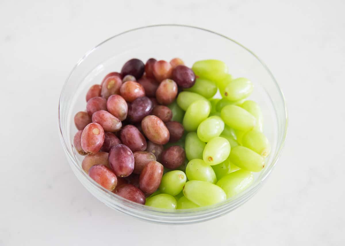 Red and green grapes in clear bowl.