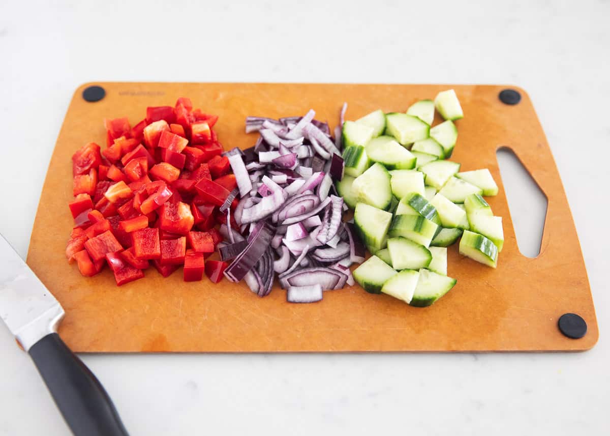 Quinoa mediterranean salad ingredients on cutting board.