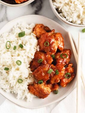Sweet and sour chicken in a serving bowl with chopsticks to the side.