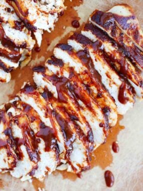Sliced bbq chicken on cutting board.