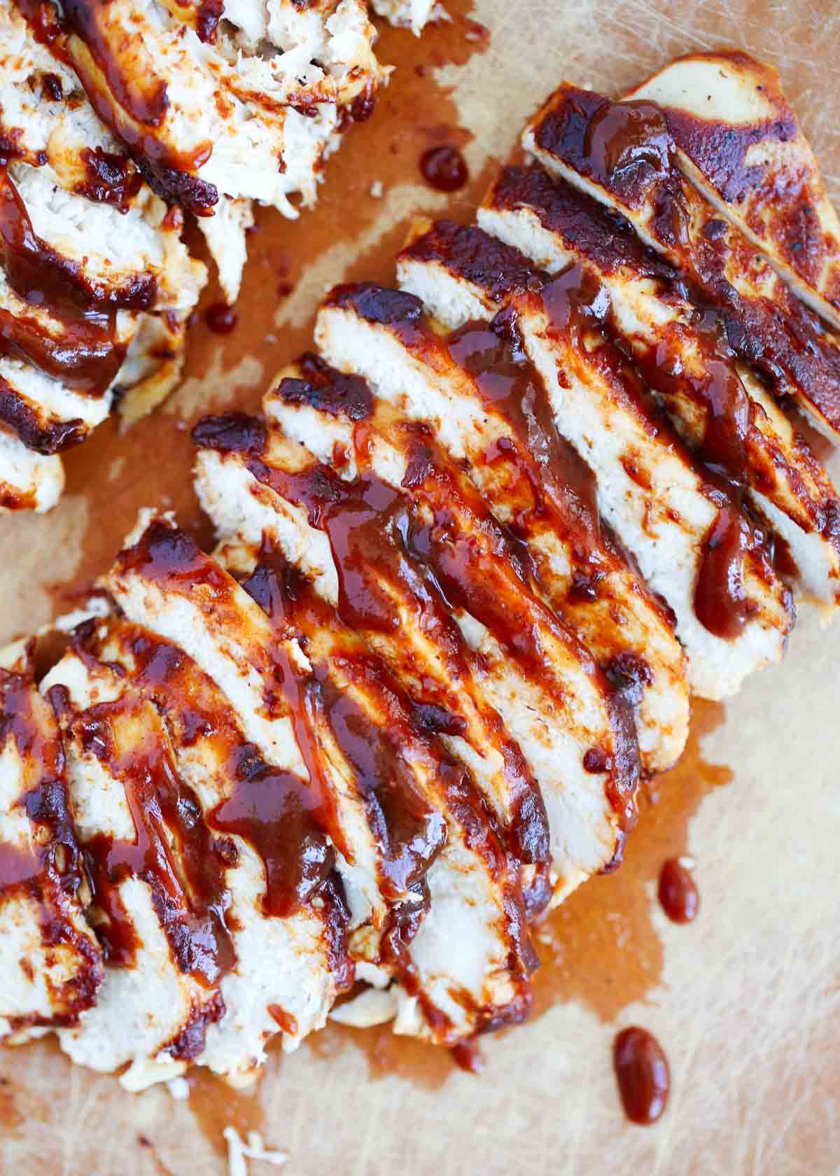 Sliced bbq chicken on cutting board.