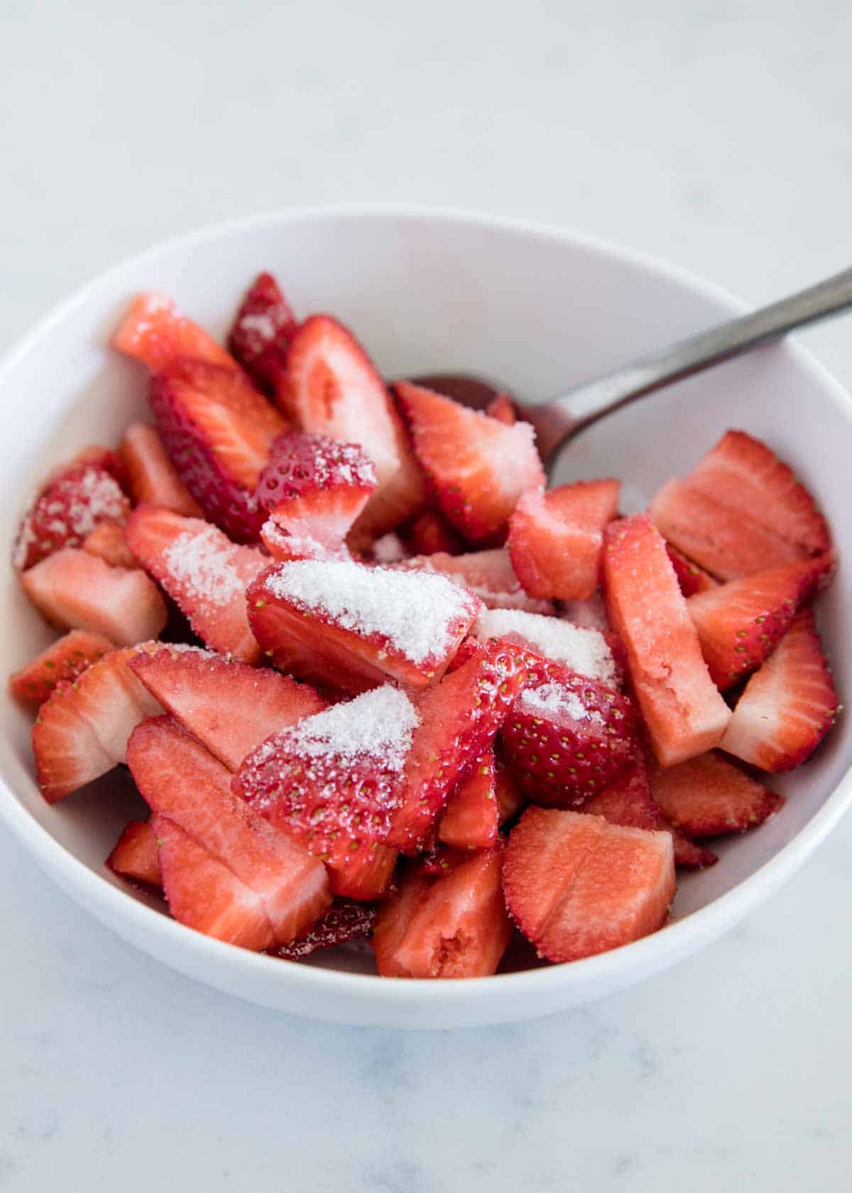 Diced strawberries in bowl with sugar on top.