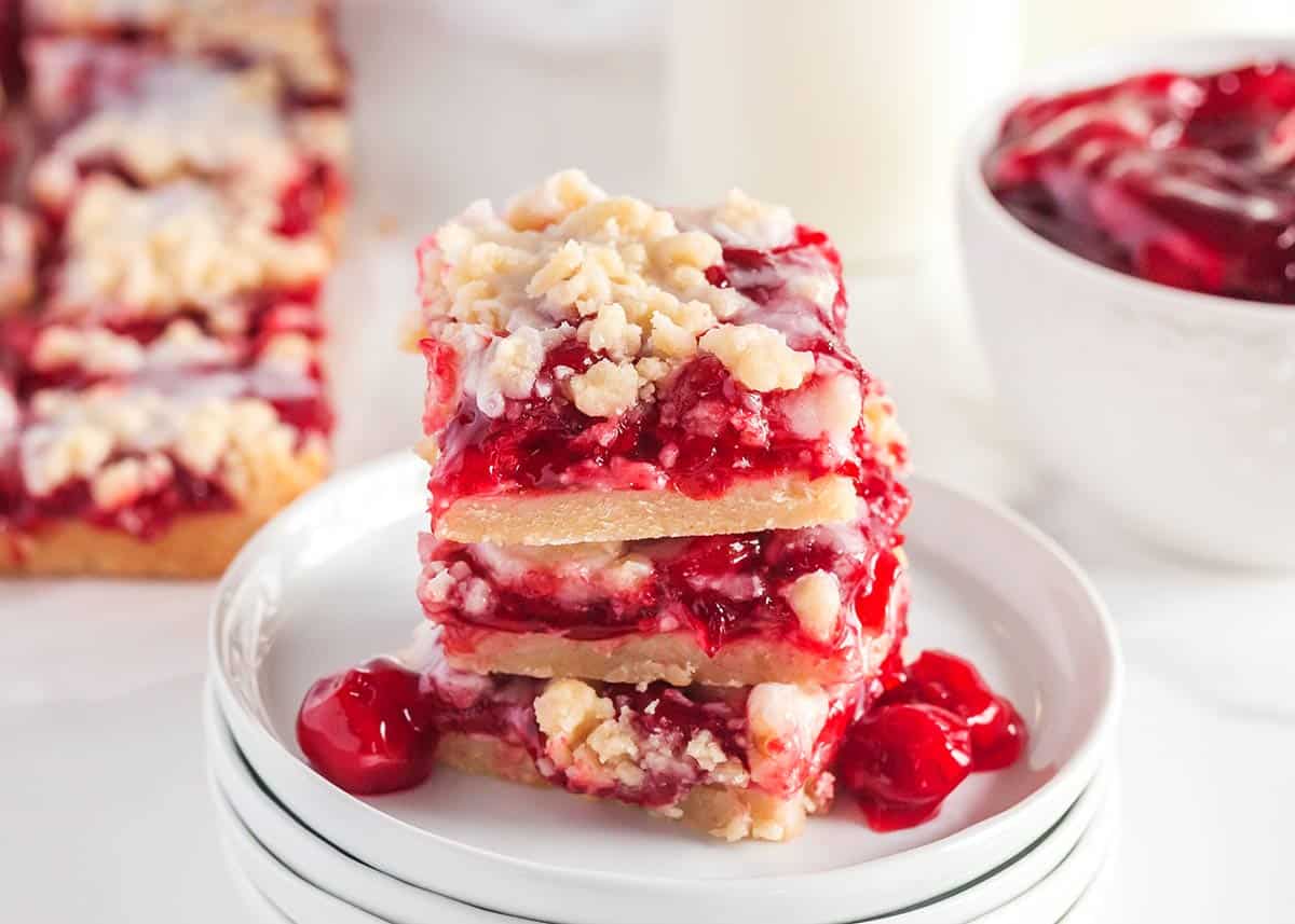 Cherry pie bars stacked on white plates.