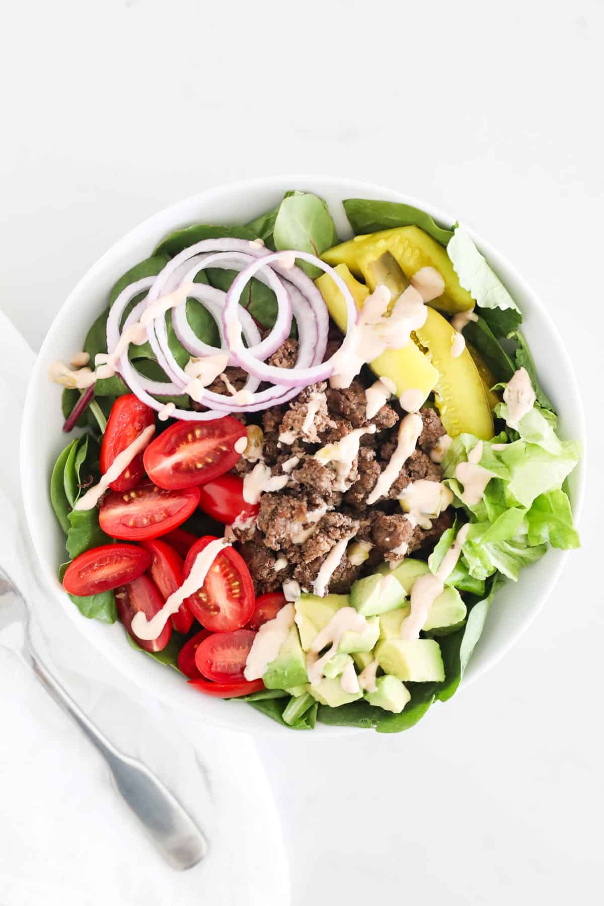 Burger salad in white bowl.