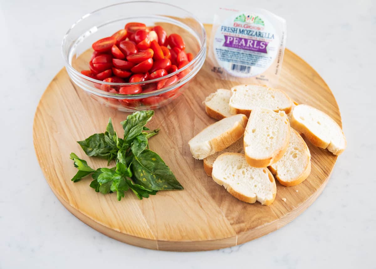 Caprese bruschetta ingredients on wooden board.