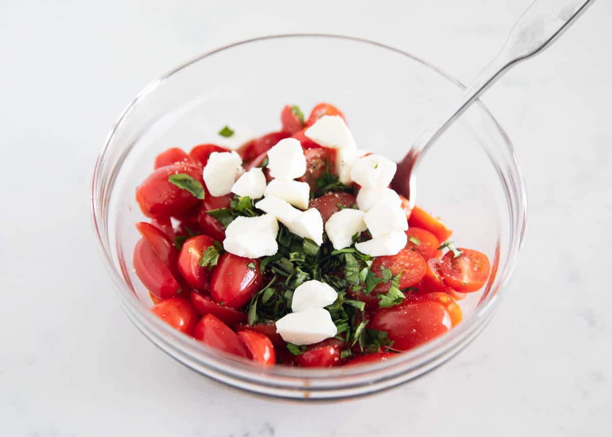 Caprese bruschetta ingredients in clear bowl.