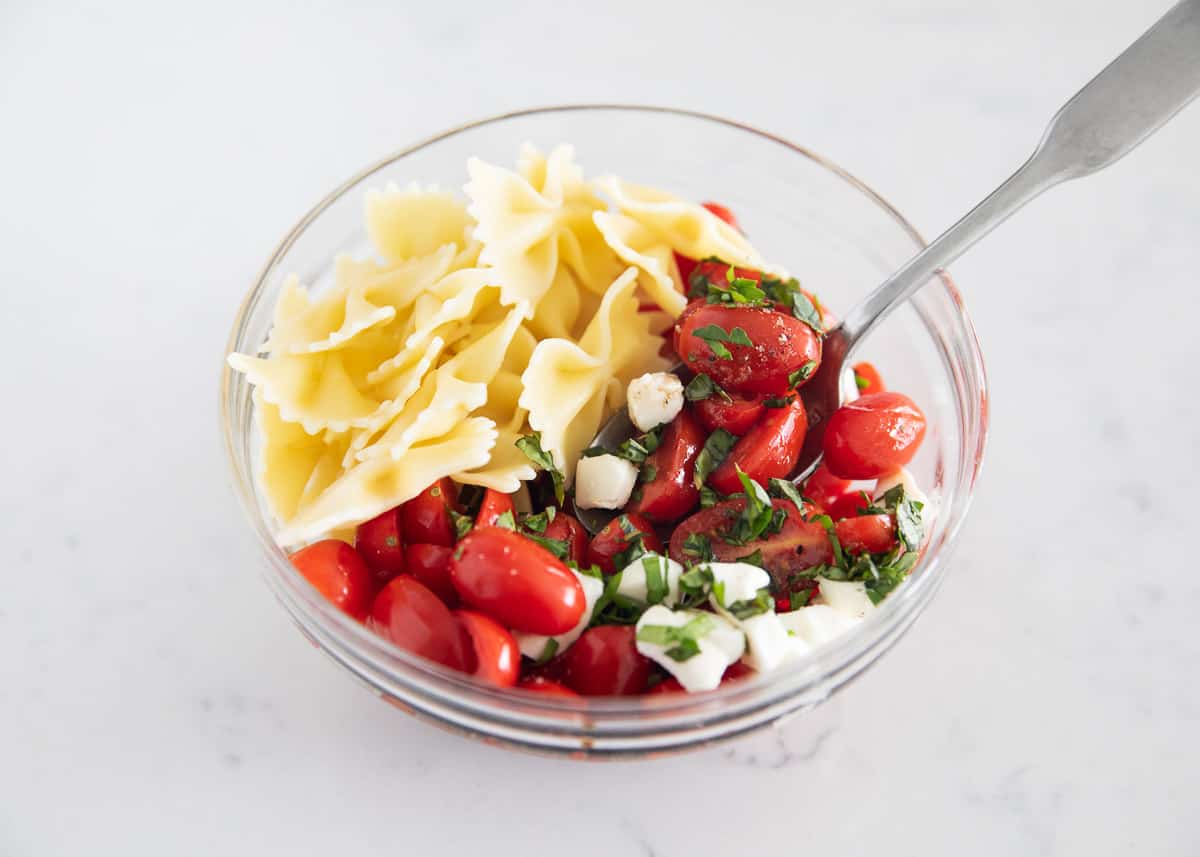 Caprese pasta salad ingredients in bowl.