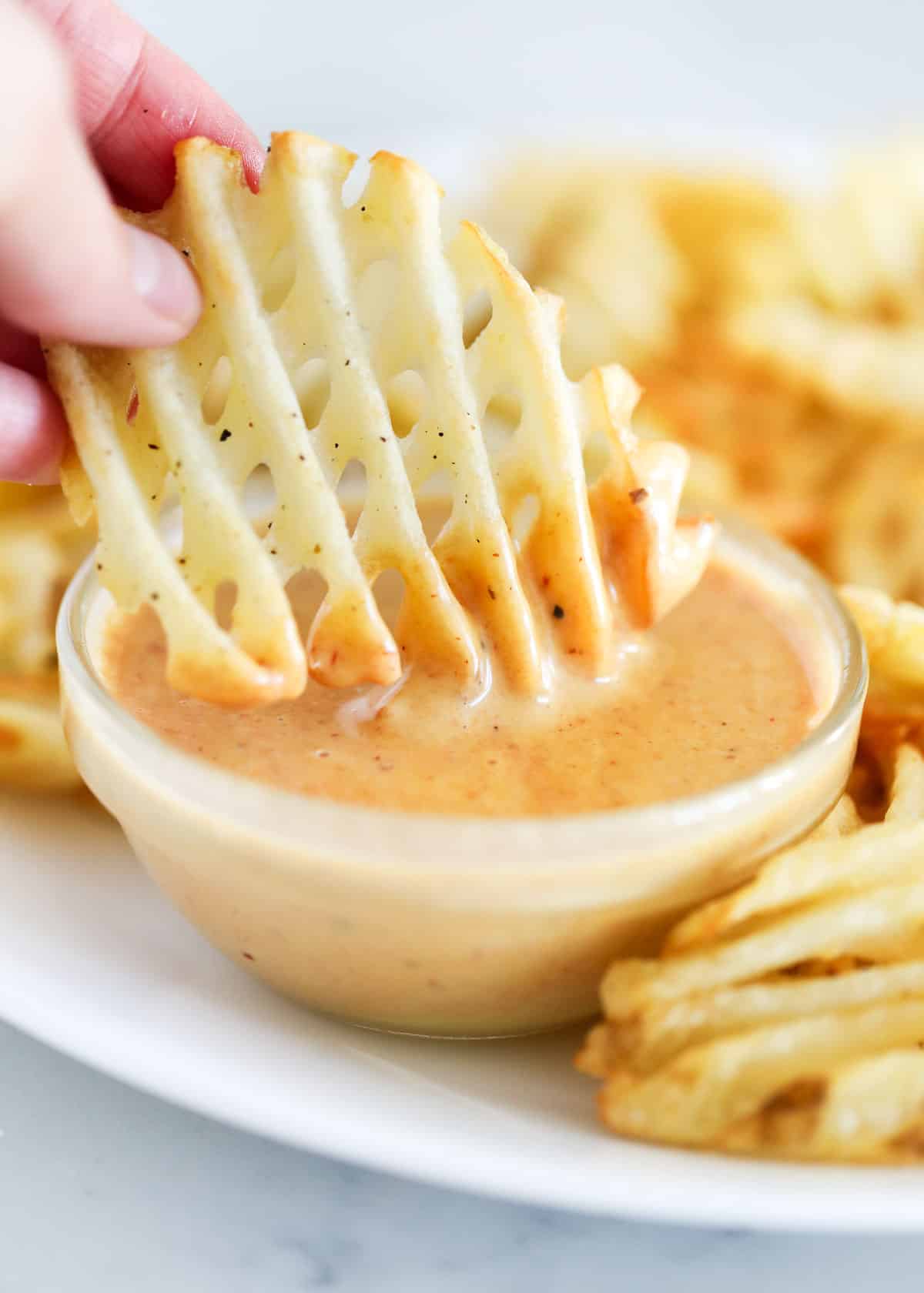Waffle fry dipped in sauce.