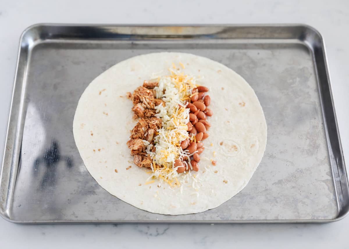 Chicken burrito being assembled on pan.