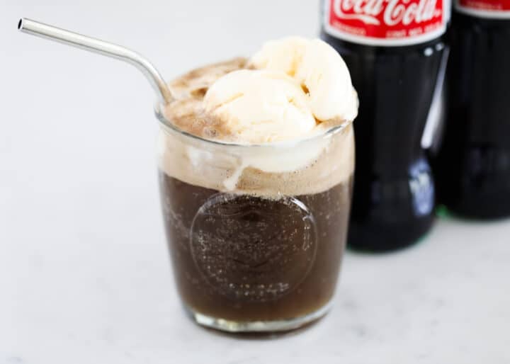 coke float in glass cup with a straw 