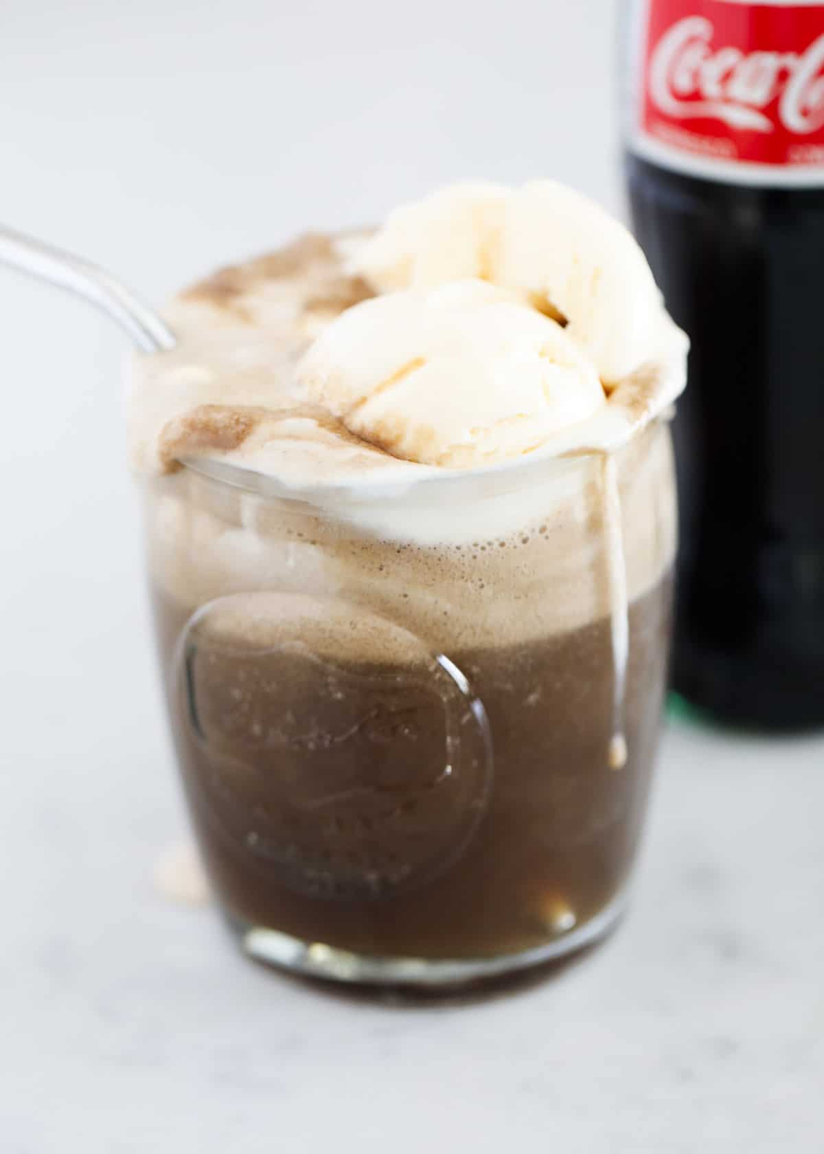 Coca cola float in glass with straw.