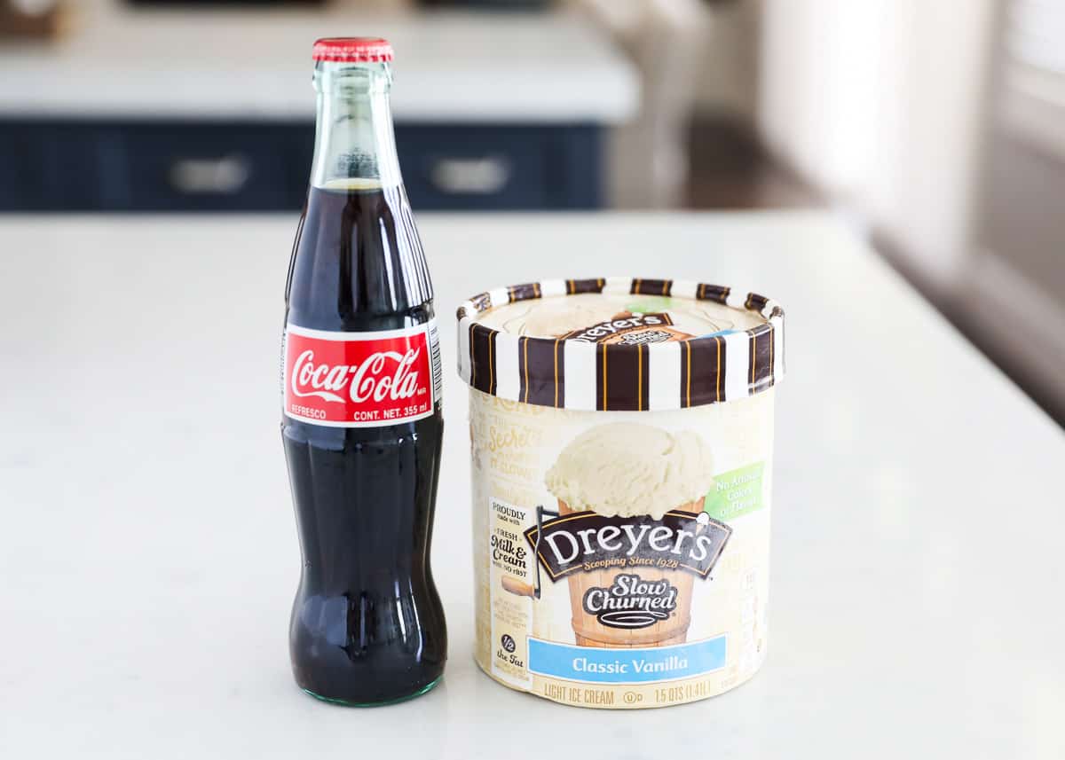 Bottle of coca cola and carton of ice cream on counter.