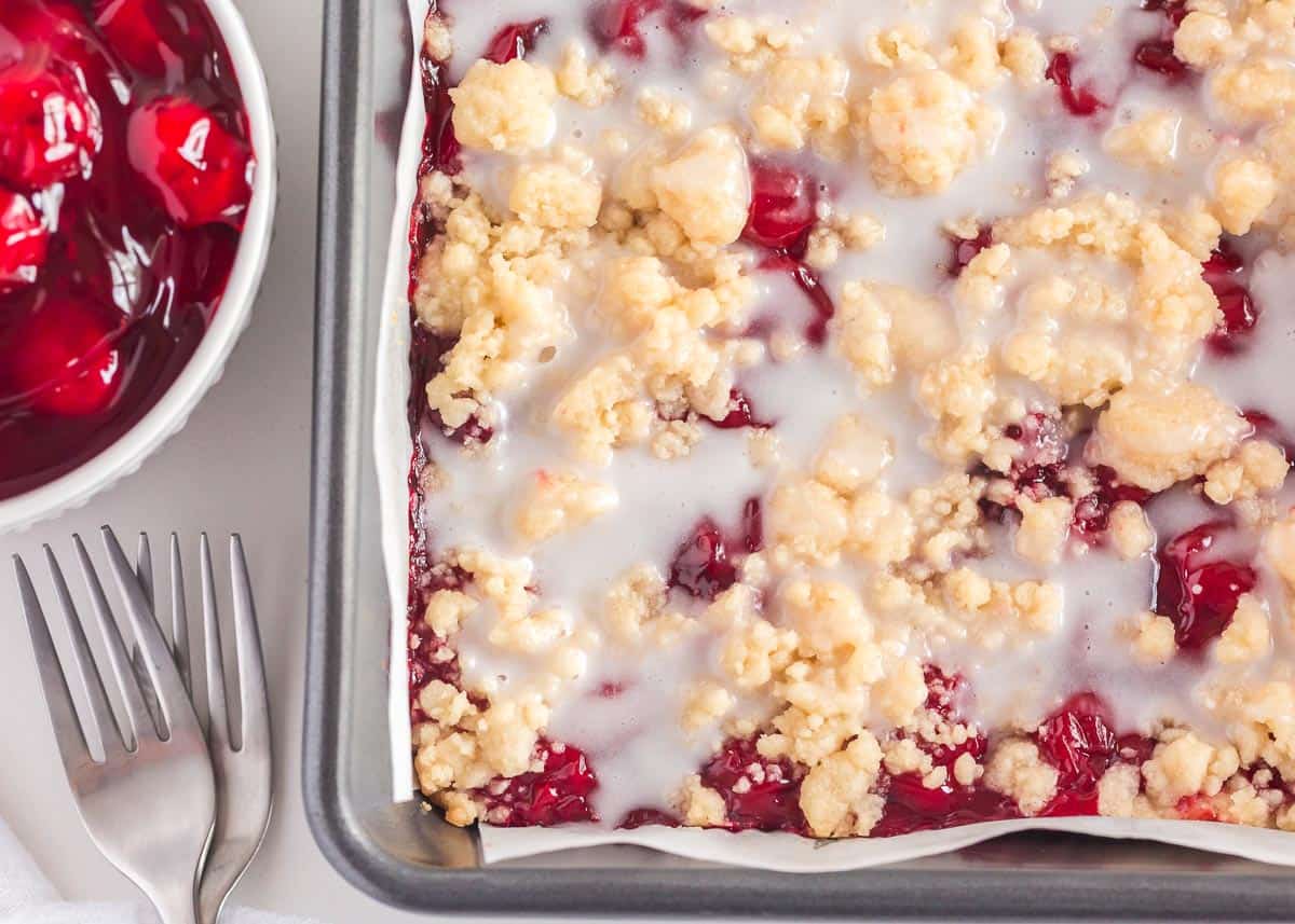 Cherry pie bars in pan with glaze.