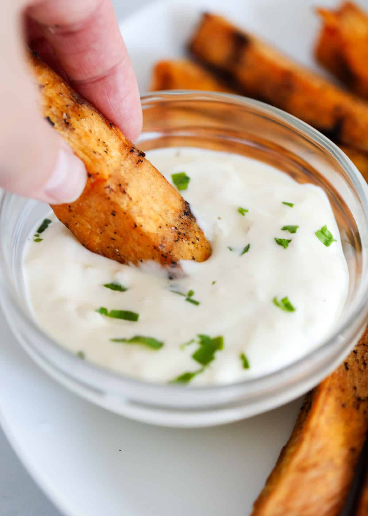 Dipping sweet potato wedge in garlic aioli.