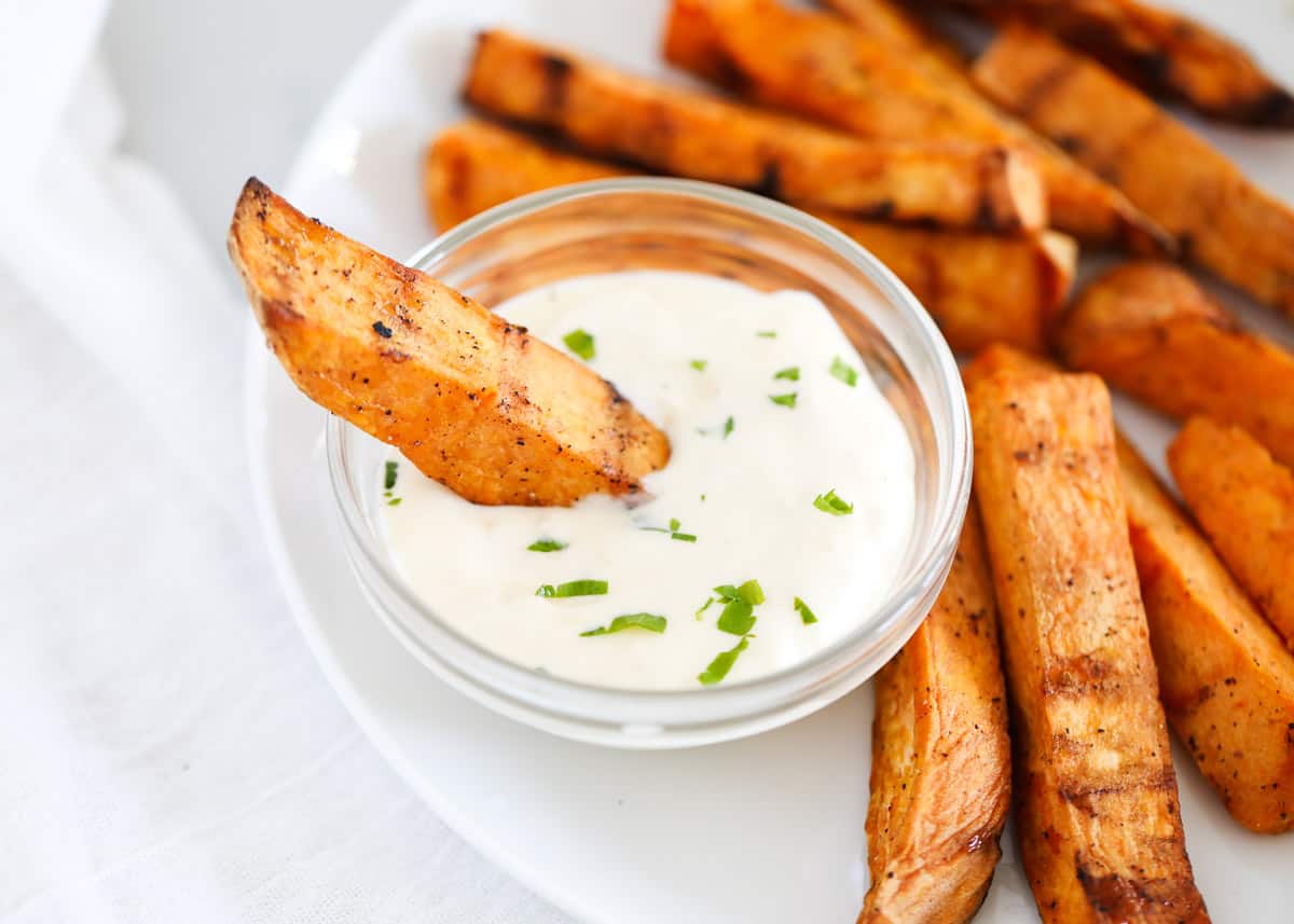 dipping sweet potato wedge in garlic aioli.