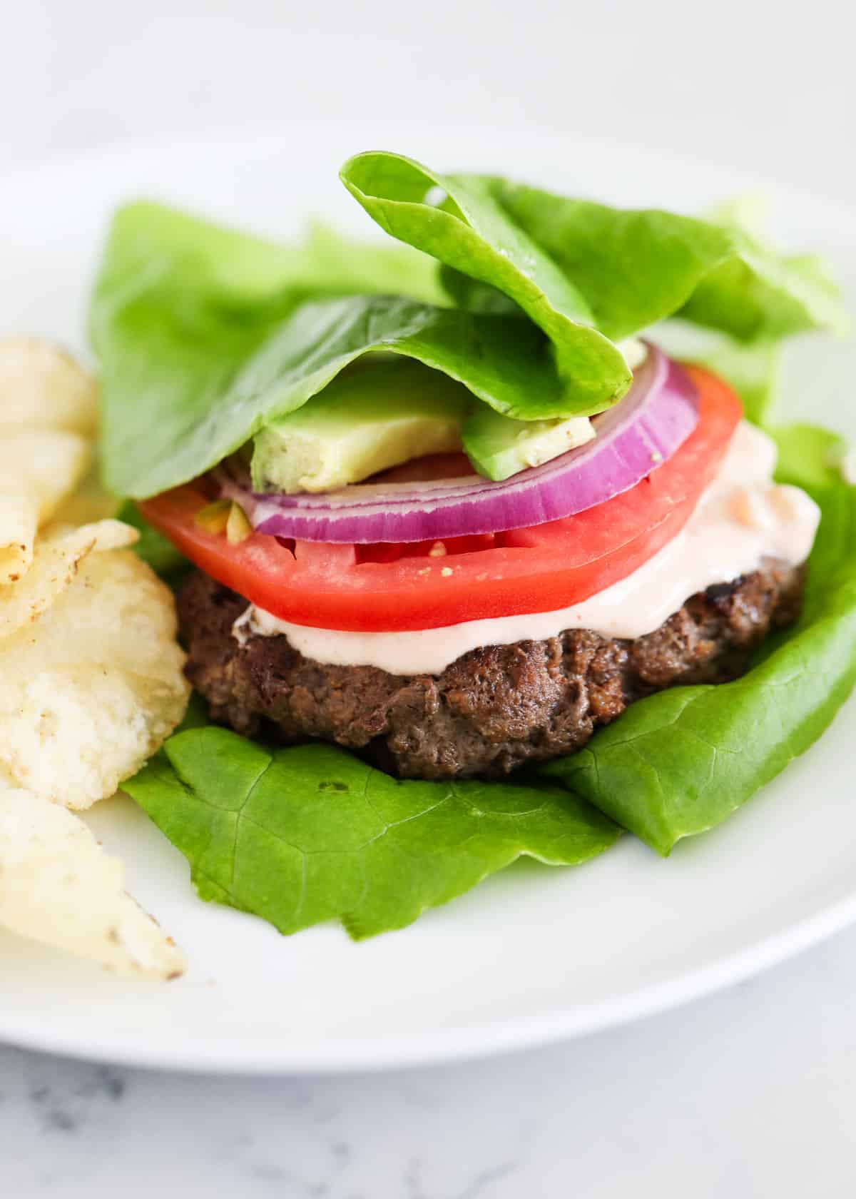 Lettuce wrap burger on white plate.