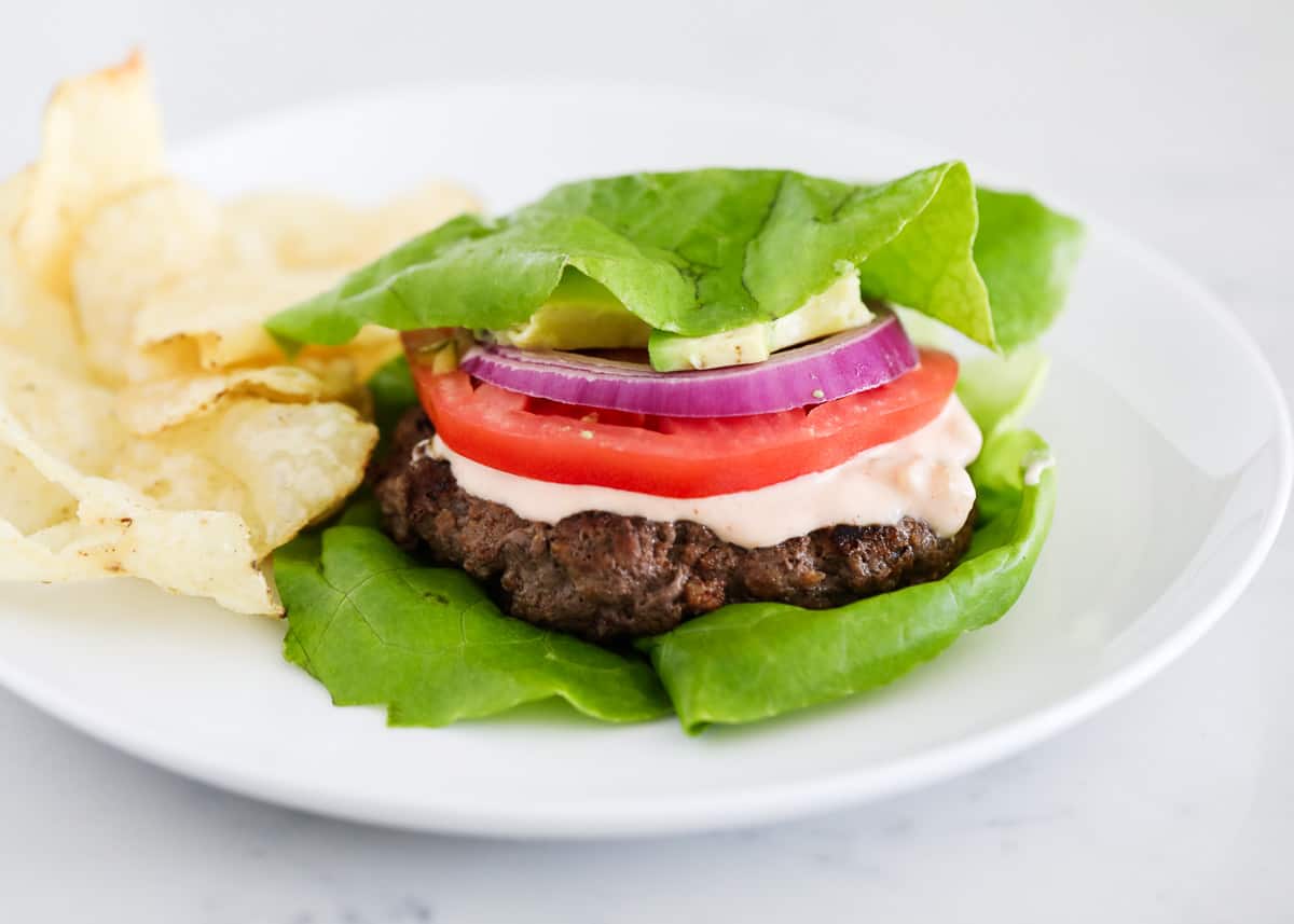 Lettuce wrap burger on white plate.