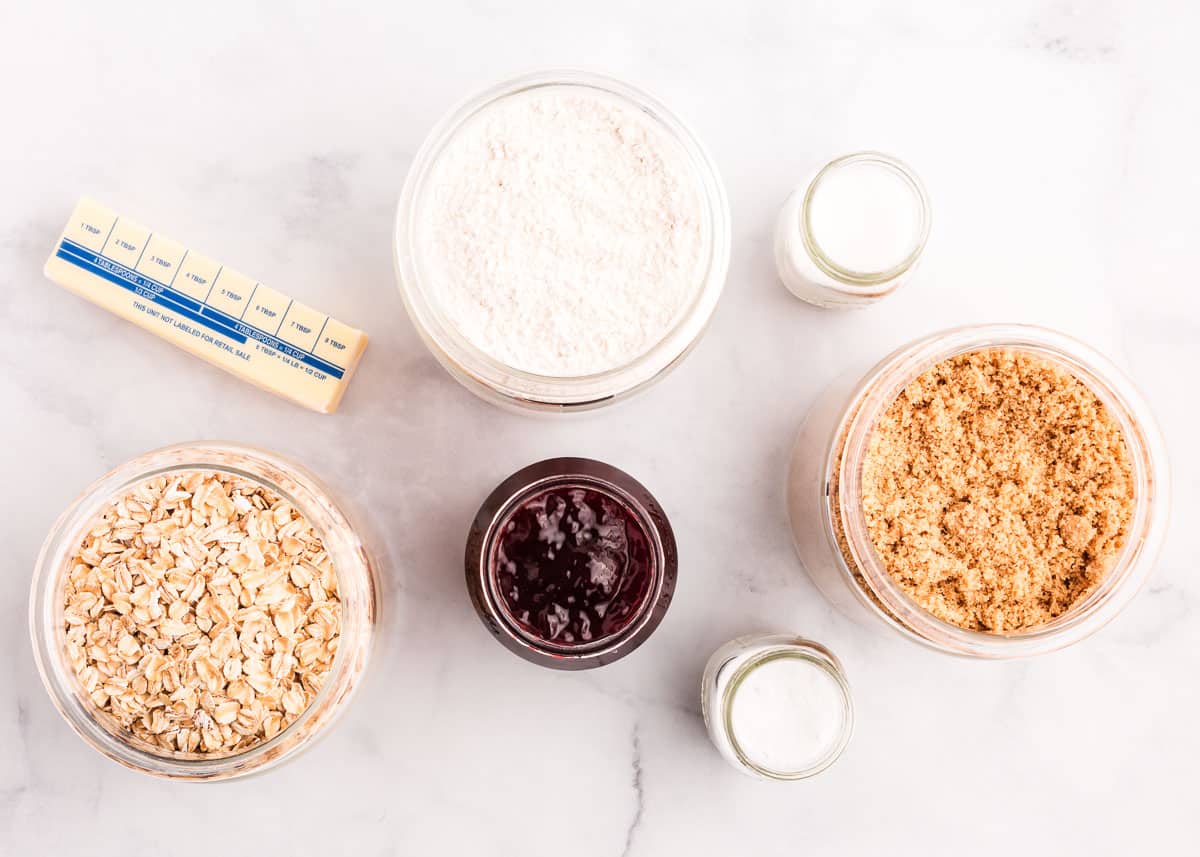 Chewy raspberry crumble bars made with a buttery oatmeal base, fresh raspberry jam and then finished off with a sprinkle more of the oatmeal crumb topping. You only need 7 ingredients and 15 minutes of prep time to make this easy summer dessert! Raspberry crumb bars ingredients on table.